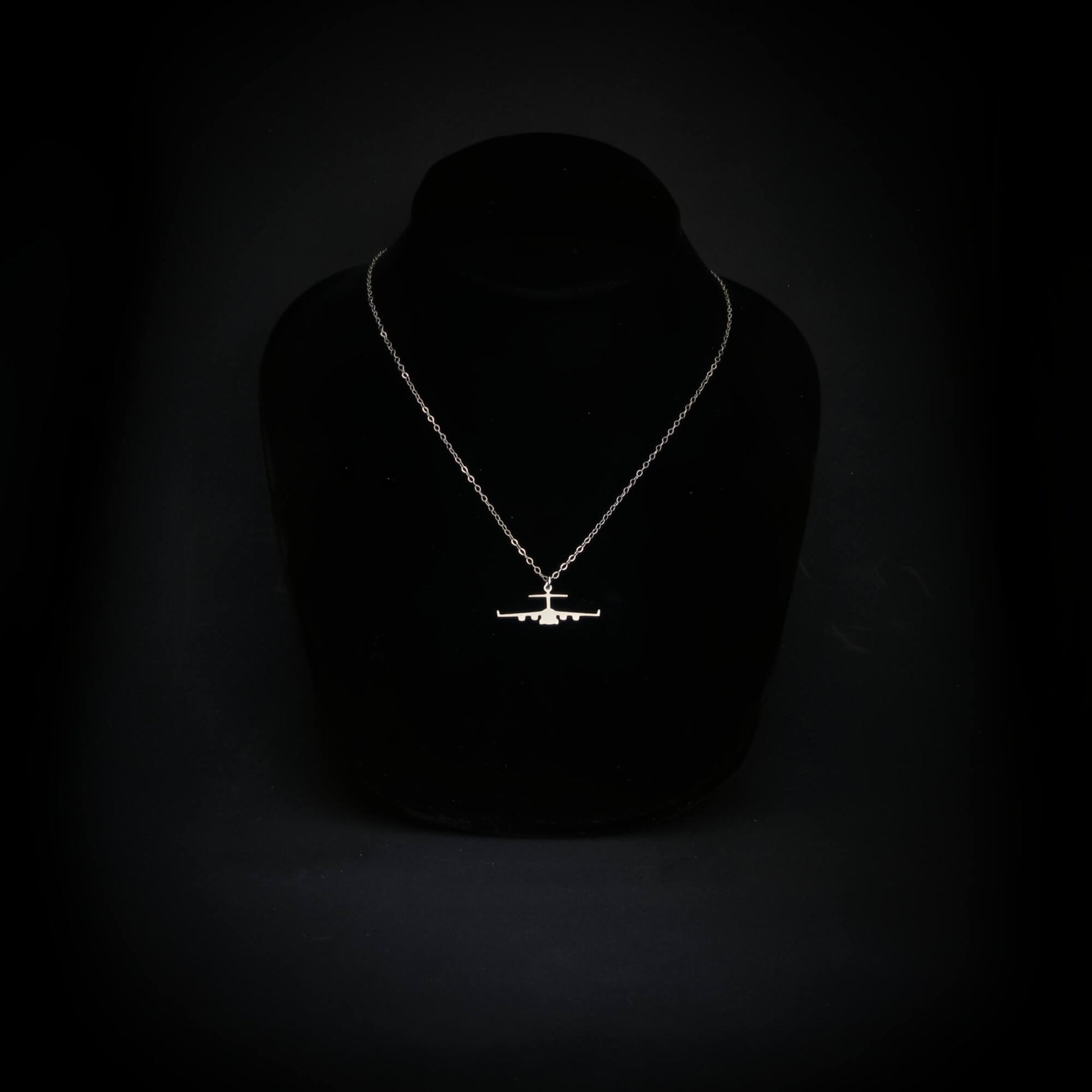 C-17 military aircraft necklace hanging on a bust, showing sterling silver silhouette and dainty matching chain