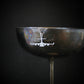 Aviation-themed C-17 aircraft necklace in silver, draped stylishly over a vintage wine glass rim