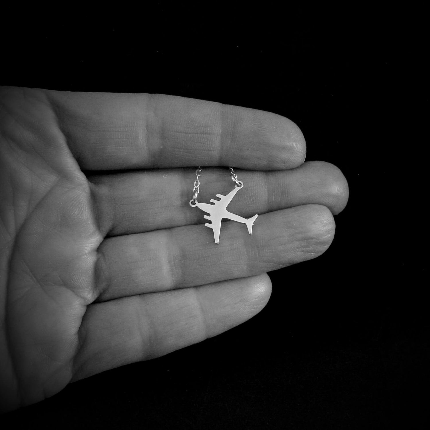 C-17 military jet necklace shown in hand for scale