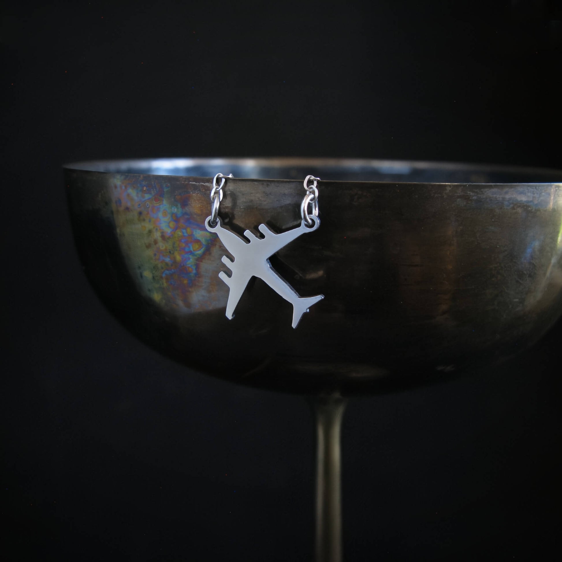 Military aircraft necklace hanging from wine glass edge