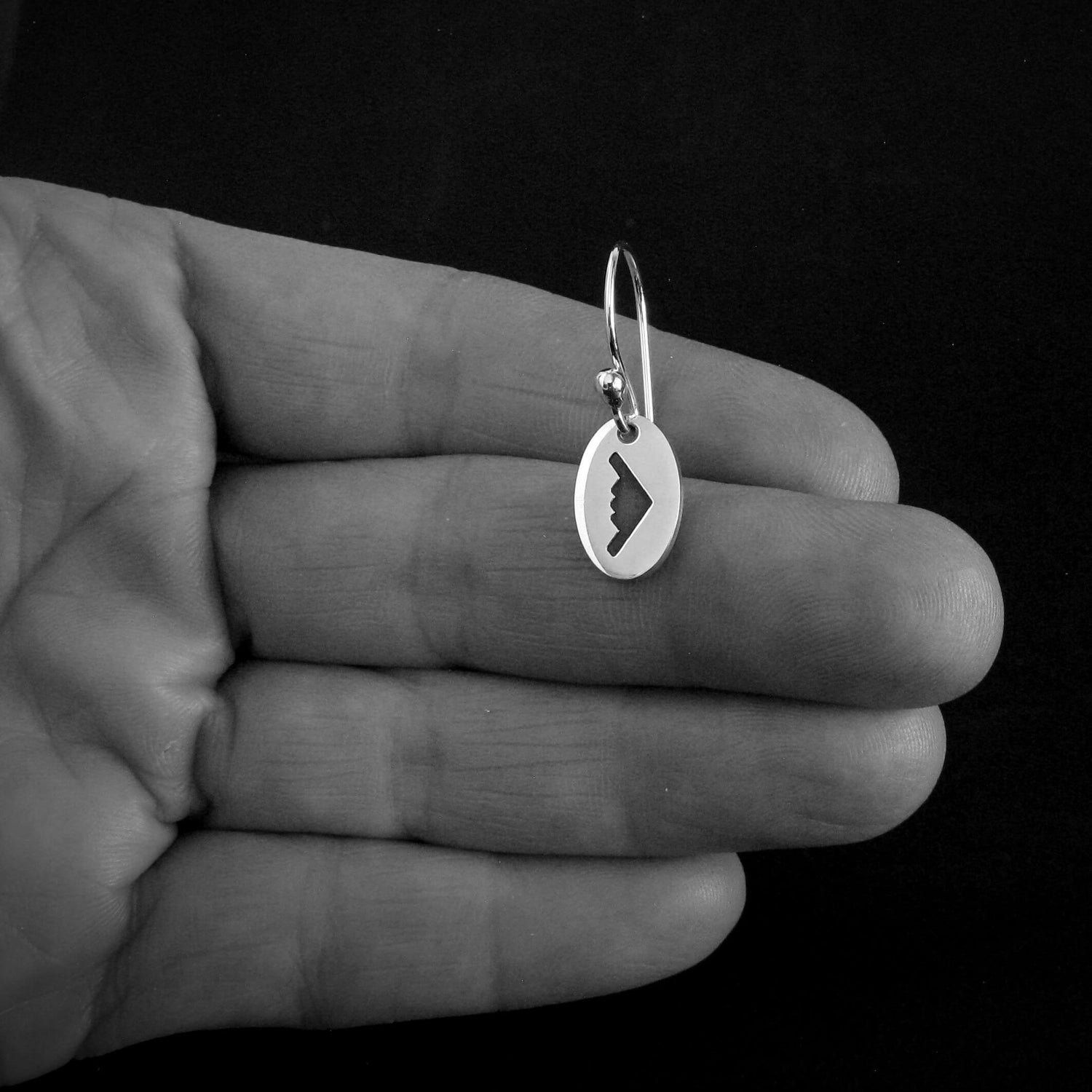Hand holding sterling silver B‑2 Spirit bomber airplane dangle earring – dainty handmade aviation jewelry