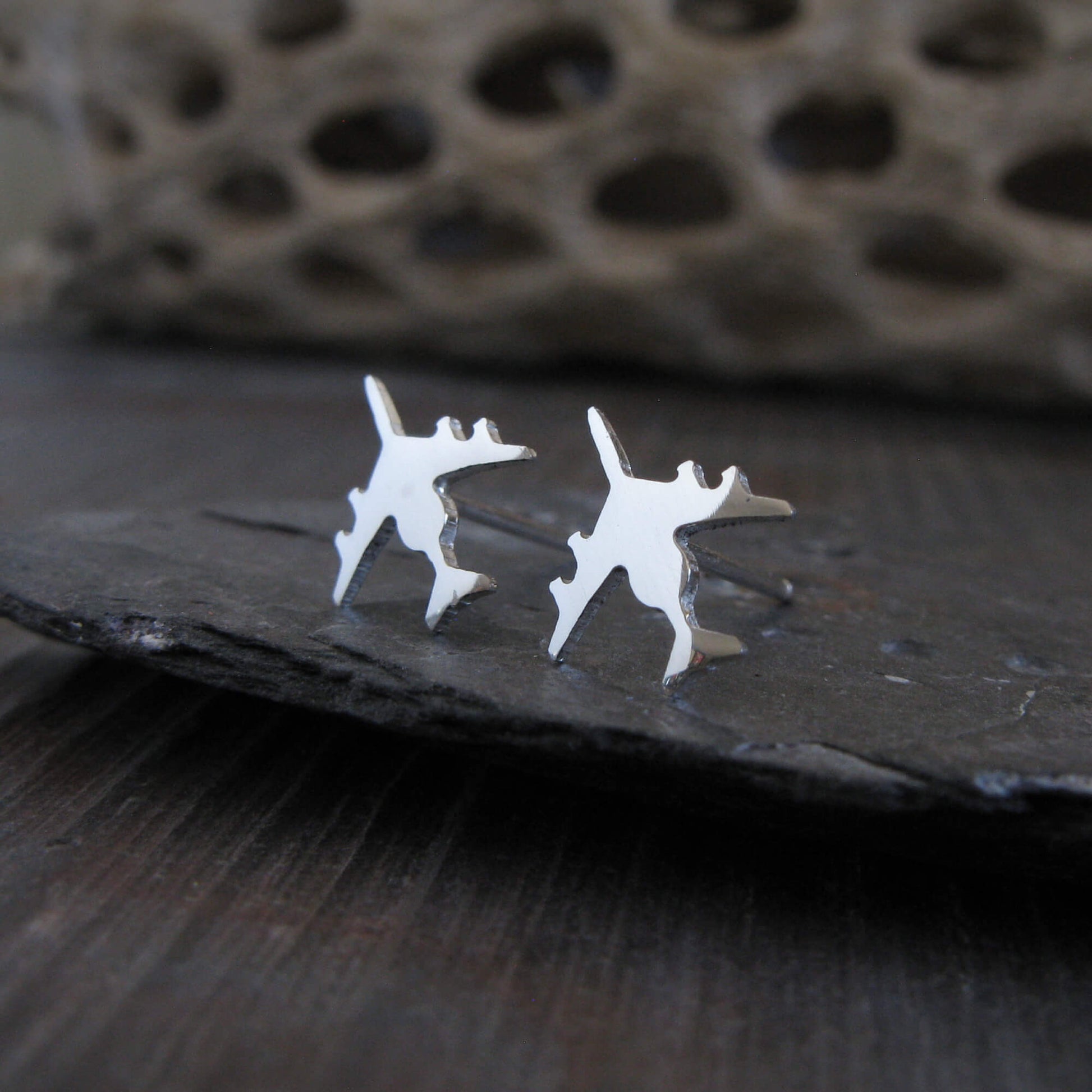 Polished Sterling Silver E-3 Sentry military jet airplane shaped stud earrings on a stone background