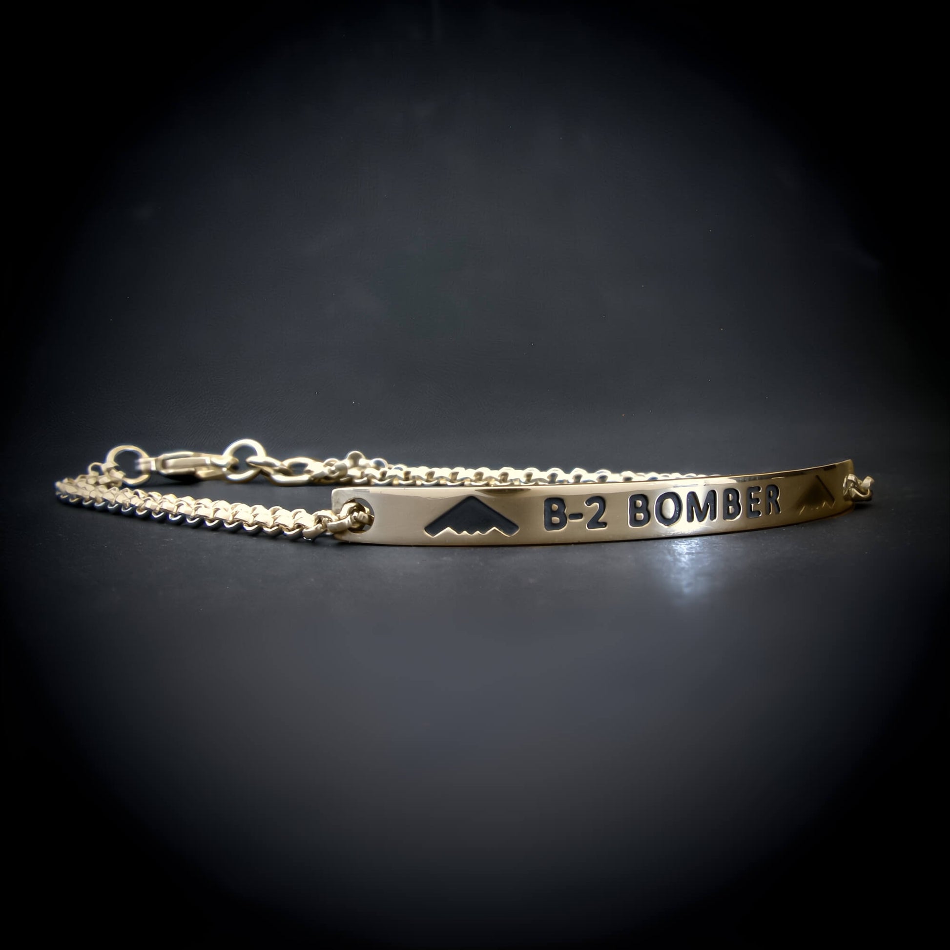 Gold bracelet with 'B-2 Bomber' engraving on a dark background