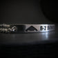 Silver bracelet with 'B-2 BOMBER' engraving on a dark background