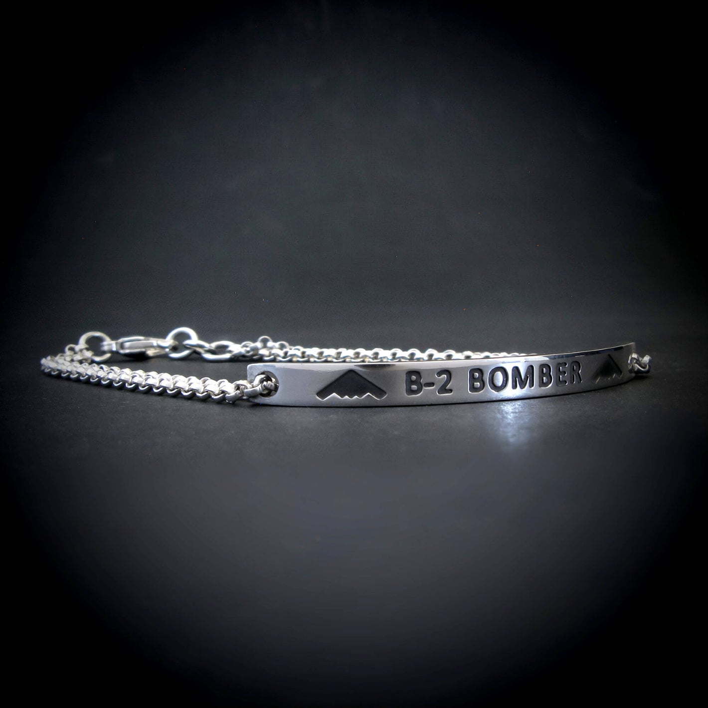 Silver bracelet with 'B-2 Bomber' engraving on a dark background