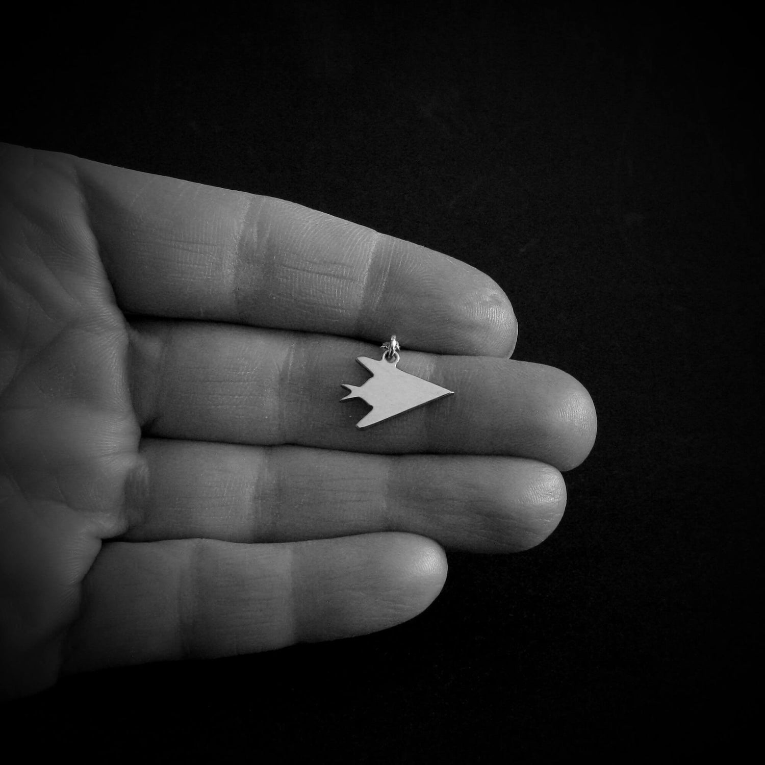 Sterling silver F-117 Nighthawk stealth jet pendant necklace shown in hand – handmade aviation military jewelry