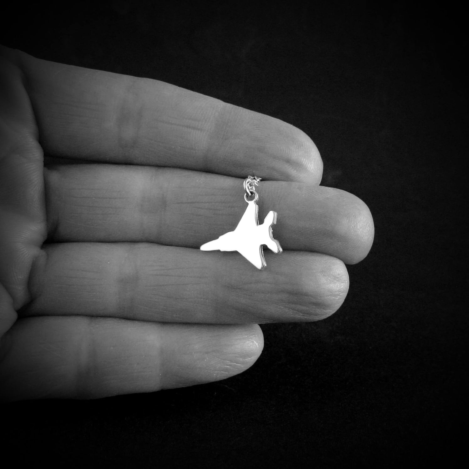 Sterling silver F-15 Eagle necklace pendant shown resting on open hand for scale