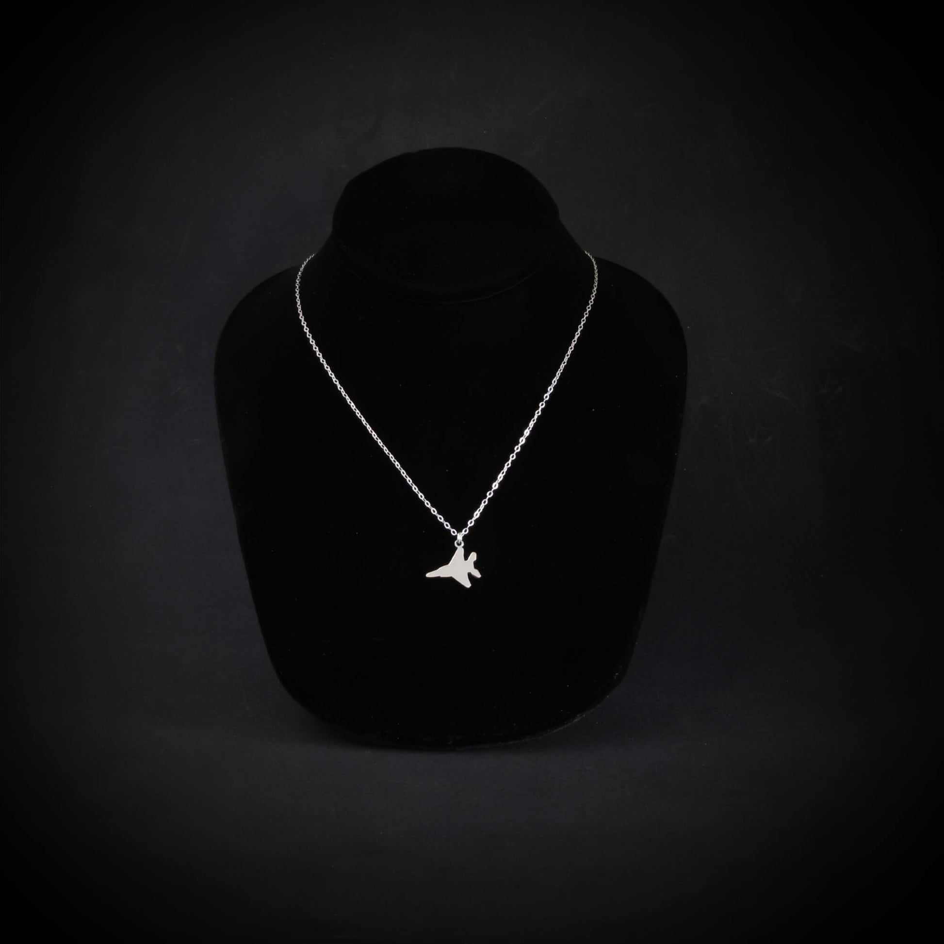 Sterling silver F-15 Eagle military jet pendant necklace displayed on black bust