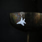 Polished sterling silver F-15 Eagle jet necklace hanging over oxidized silver goblet