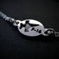 Silver bracelet with a round tag featuring an F-16 military fighter jet on a black background