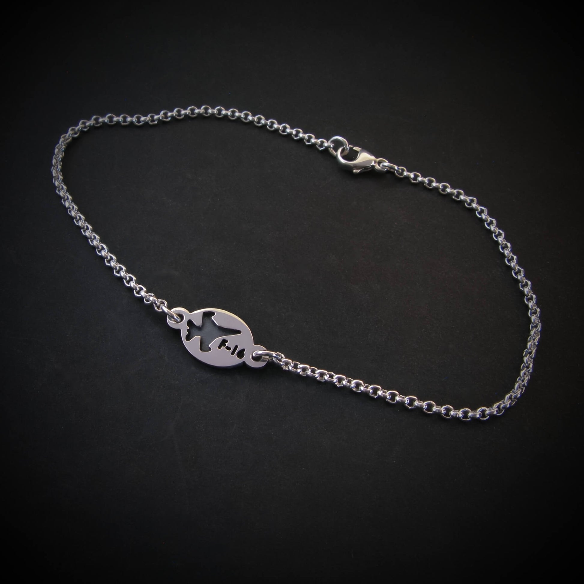Silver bracelet with a round tag featuring an F-16 military fighter jet on a black background