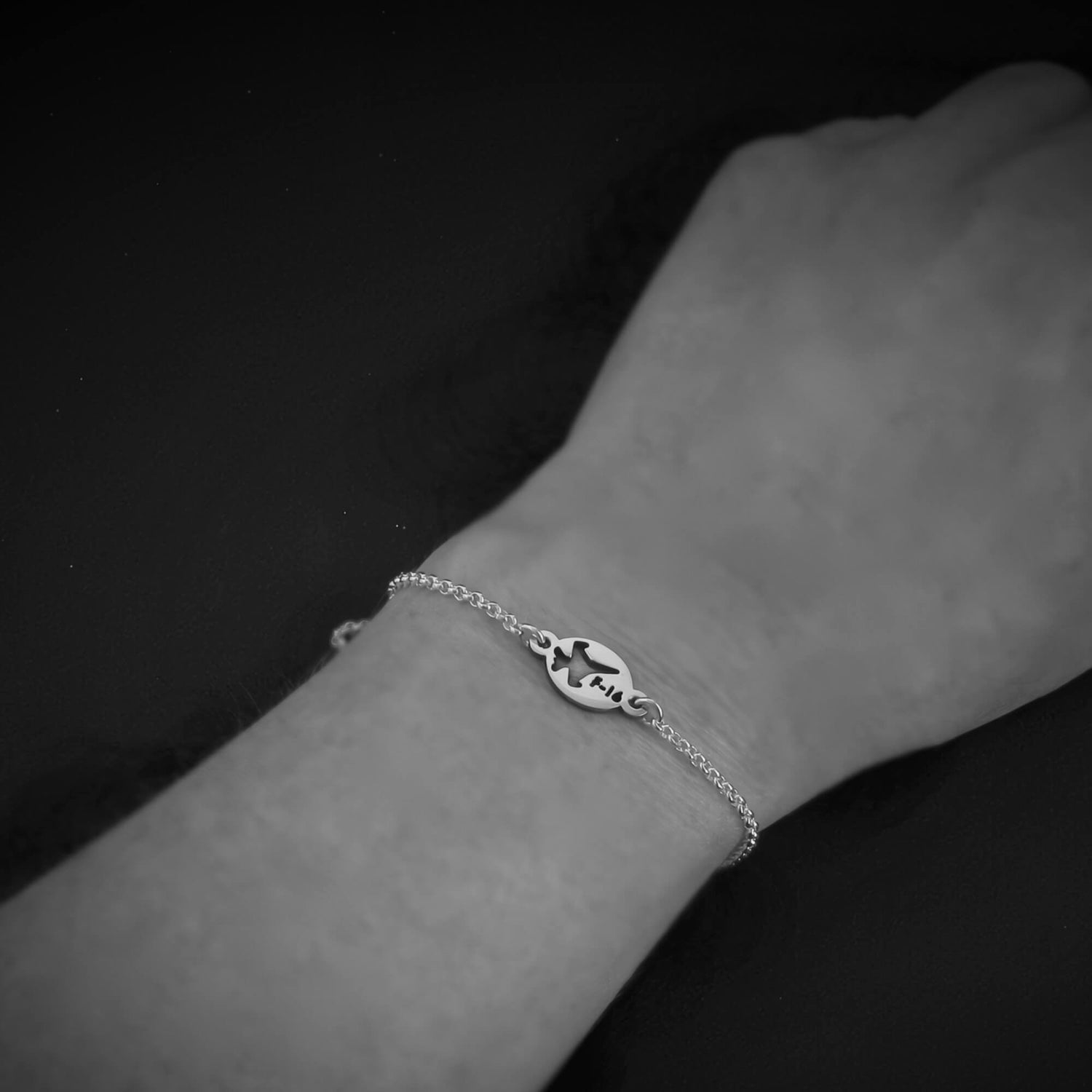 Silver F-16 Military Jet bracelet on a wrist against a dark background