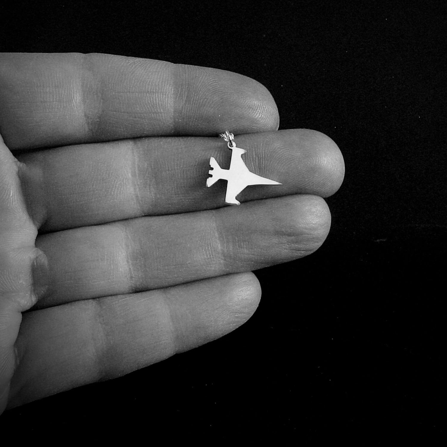 Handmade sterling silver F-16 Viper fighter jet pendant necklace shown in hand for size – artisan military aviation jewelry gift