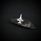 Silver F-16 Military jet fighter airplane tie tack on a dark stone surface with a black background