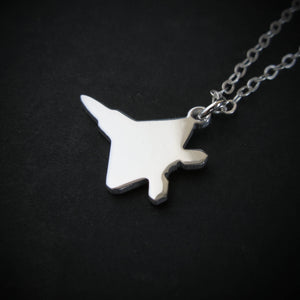Close-up of the sterling silver F-22 Raptor pendant on chain against black background