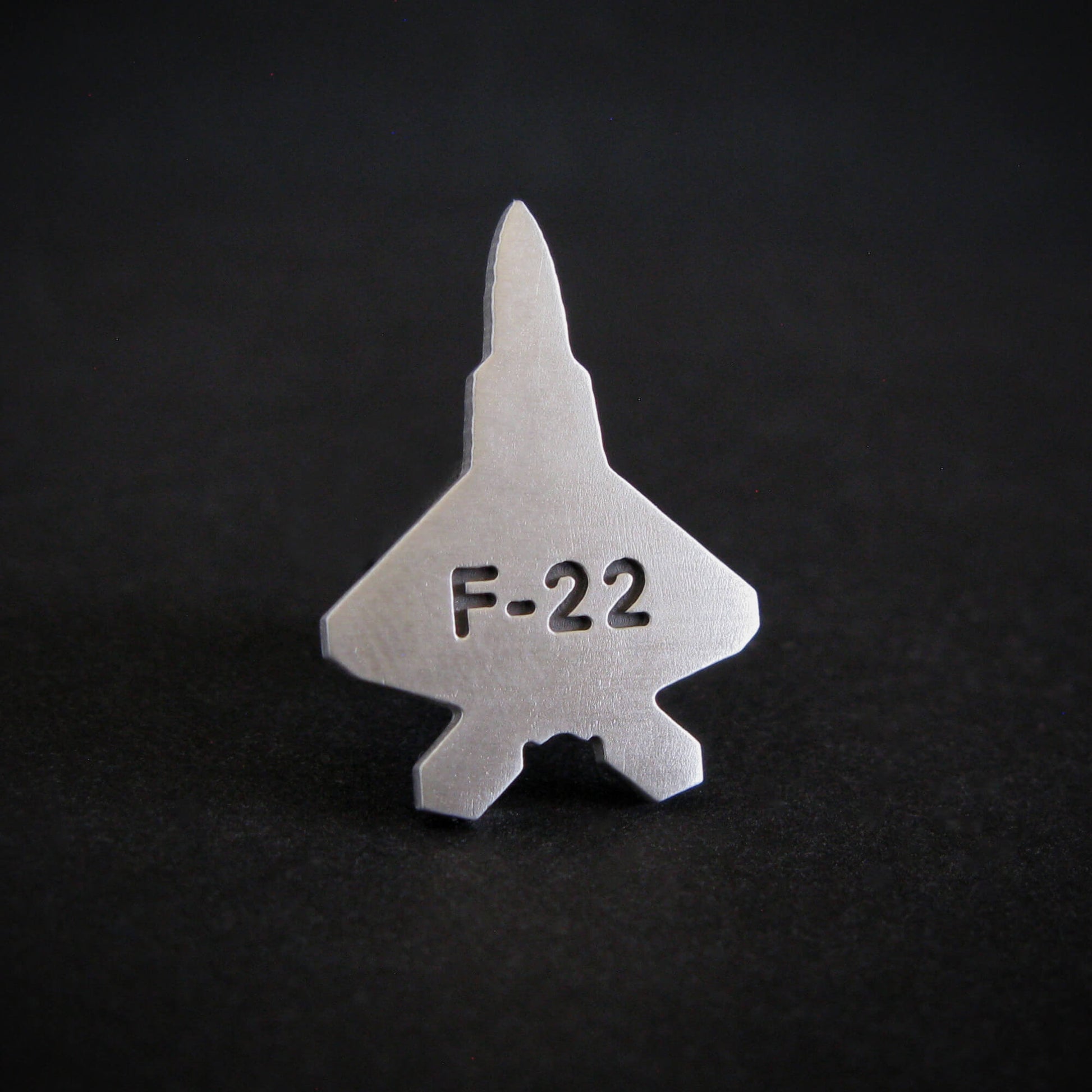 Silver F-22 military aviation fighter jet tie tack on a black background