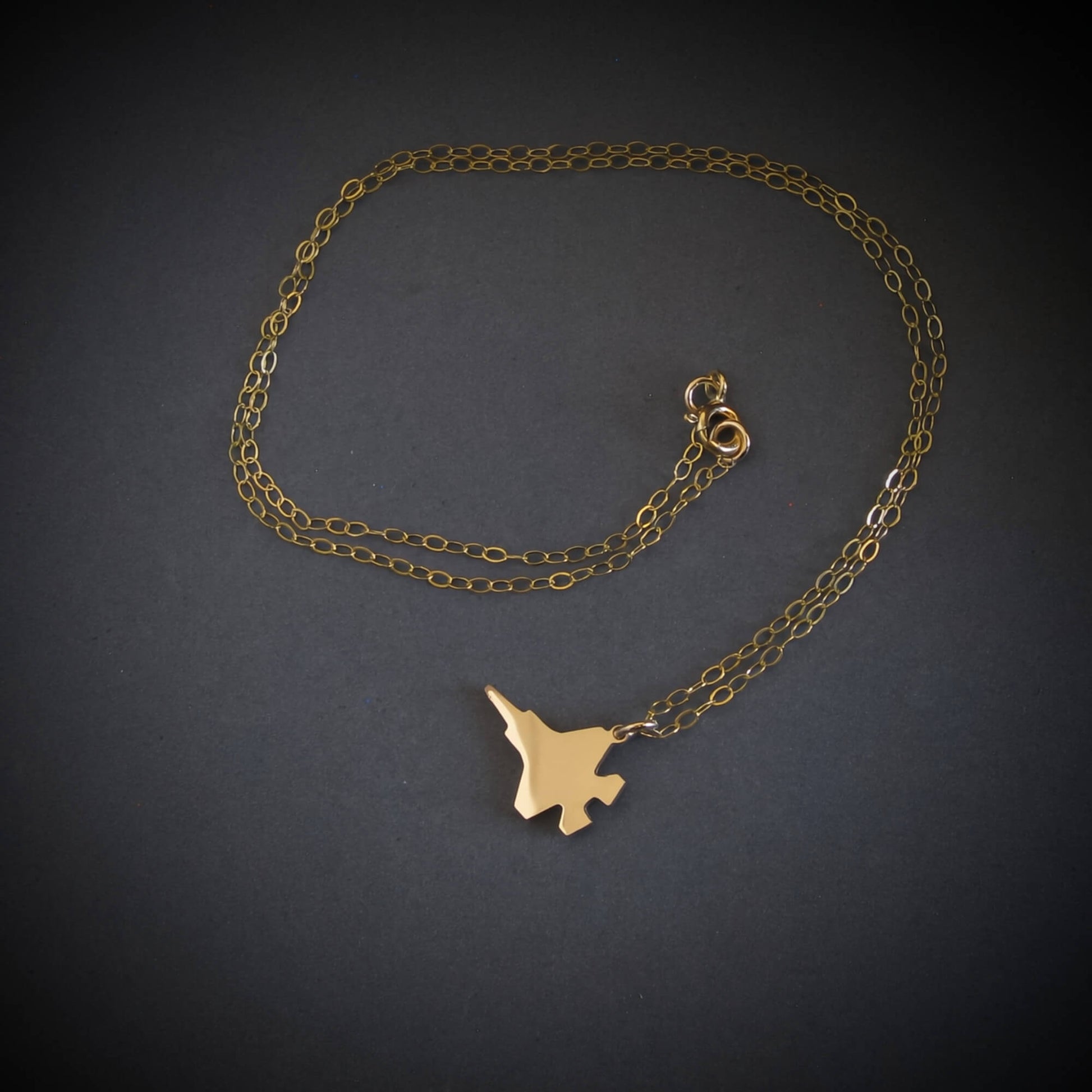 14k gold F-35 Military Fighter Jet pendant on a chain against a black background