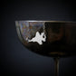 Silver F-35 Fighter Jet hanging from a wine glass against a dark background