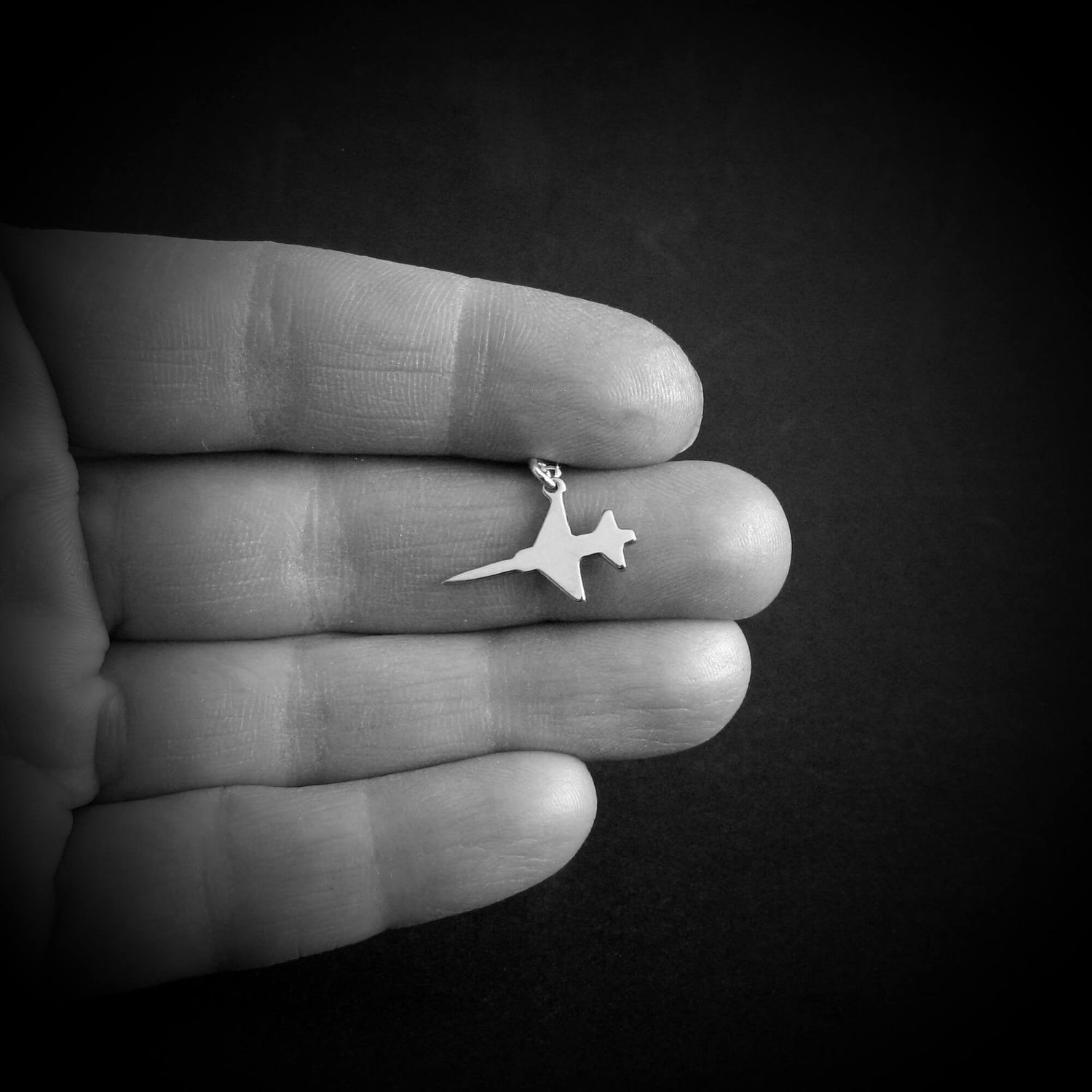 Sterling silver F-5 Freedom Fighter jet airplane pendant necklace shown in hand – handmade aviation jewelry