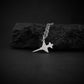 Sterling silver F-5 Freedom Fighter Jet Airplane pendant necklace resting on black rock – handmade military aviation jewelry
