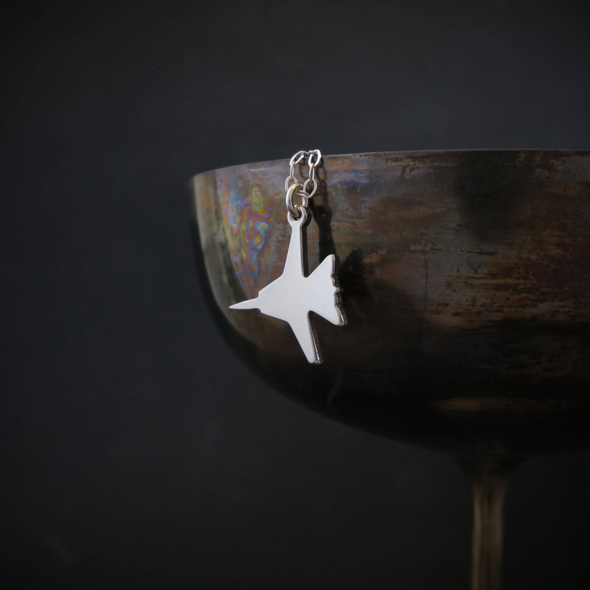 Sterling silver F-14 Tomcat jet fighter pendant necklace hanging on vintage goblet, handcrafted aviation jewelry