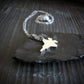 Sterling Silver F-35 Military Fighter Jet pendant on a chain on a stone surface