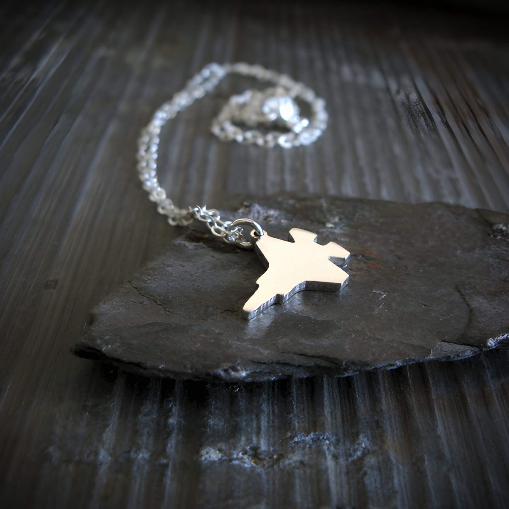 Sterling Silver F-35 Military Fighter Jet pendant on a chain on a stone surface