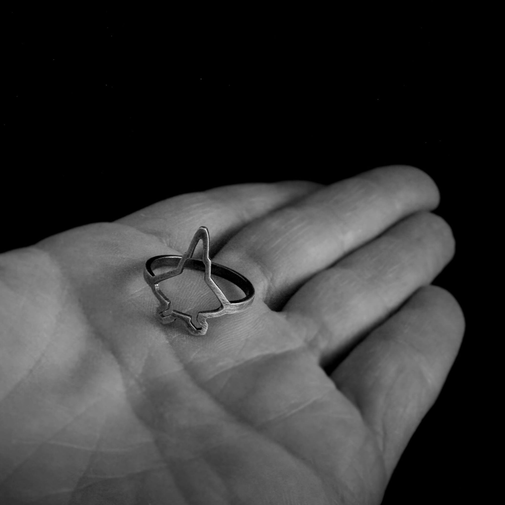 Hand holding sterling silver F‑22 Raptor fighter jet silhouette ring – handmade aviation jewelry
