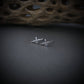 Polished sterling silver MQ-9 Reaper drone stud earrings, handcrafted with aircraft detailing, displayed on a dark surface with natural textured background.