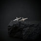 Sterling silver MQ-9 Reaper drone stud earrings, handcrafted with precision, displayed on a rugged black rock against a dark background.