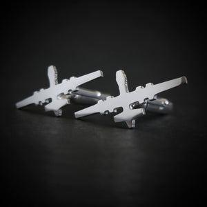 Close-up of polished sterling silver MQ-9 Reaper cufflinks with jet silhouette design on black surface