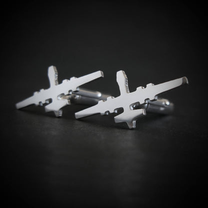 Close-up of polished sterling silver MQ-9 Reaper cufflinks with jet silhouette design on black surface