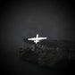 Silver MQ-9 Reaper Military Drone airplane tie pin on a dark rock with a dark background