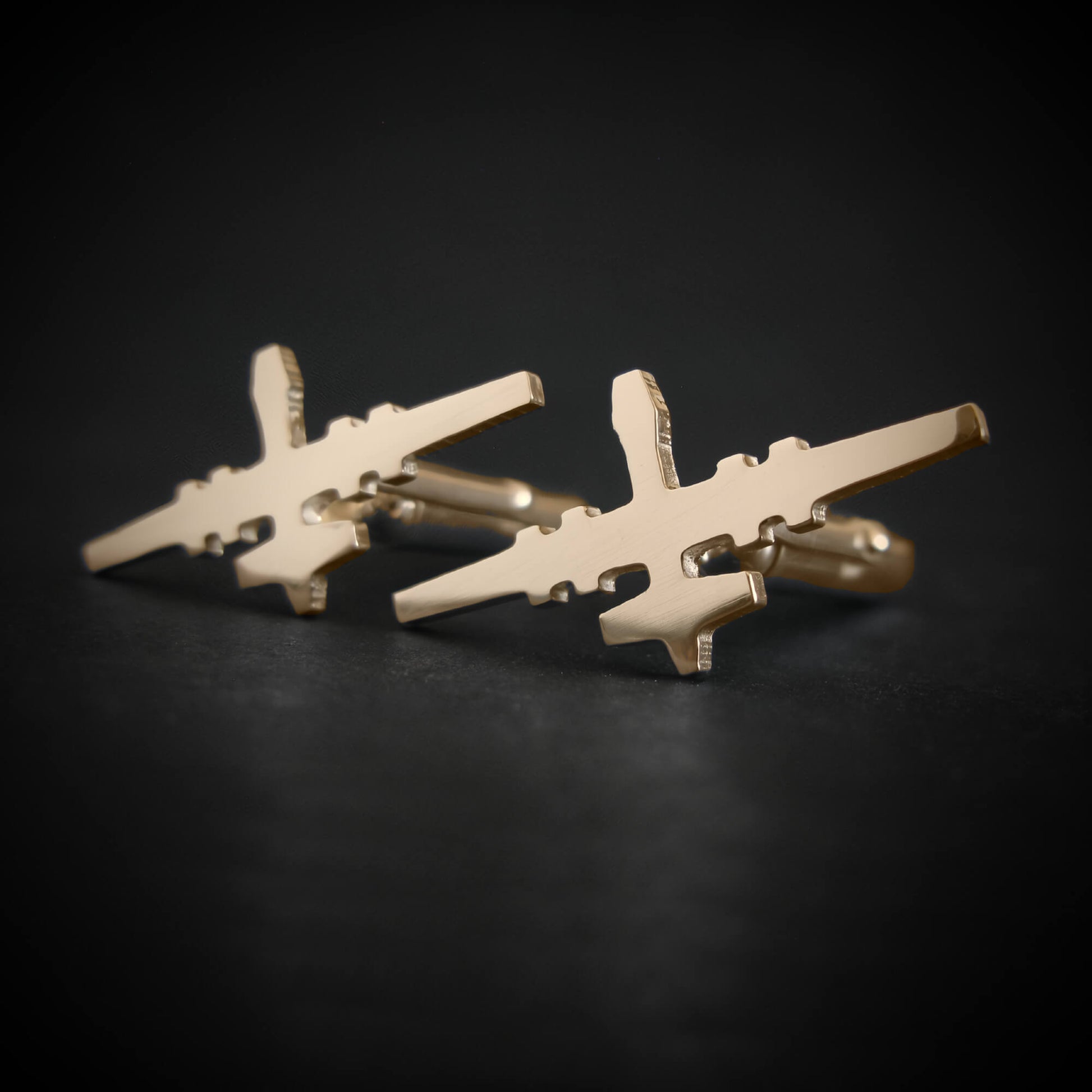 Close-up of MQ-9 Reaper drone cufflinks in polished 14k gold on dark background