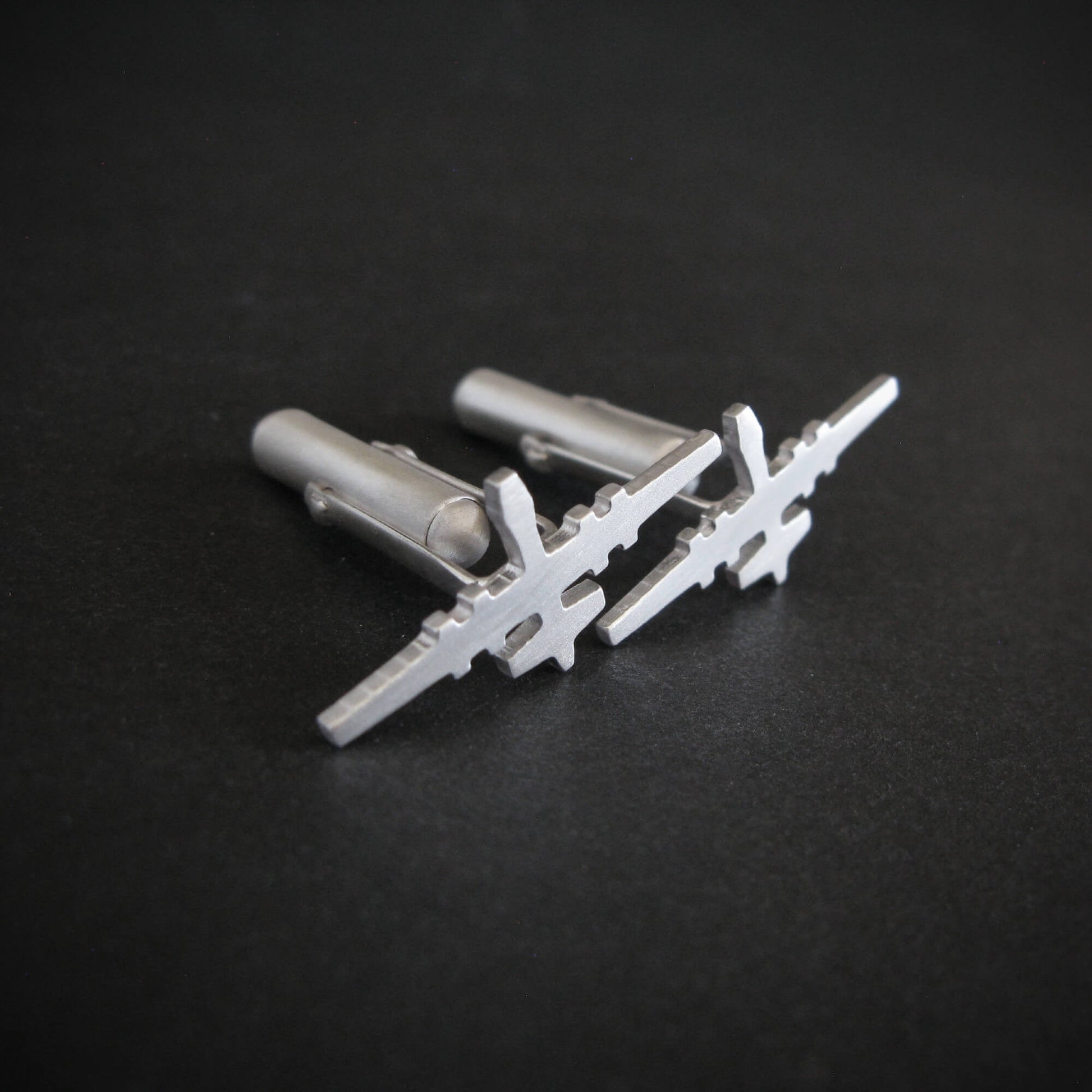 Angled view of MQ-9 Reaper cufflinks in satin sterling silver finish with bullet-back closures
