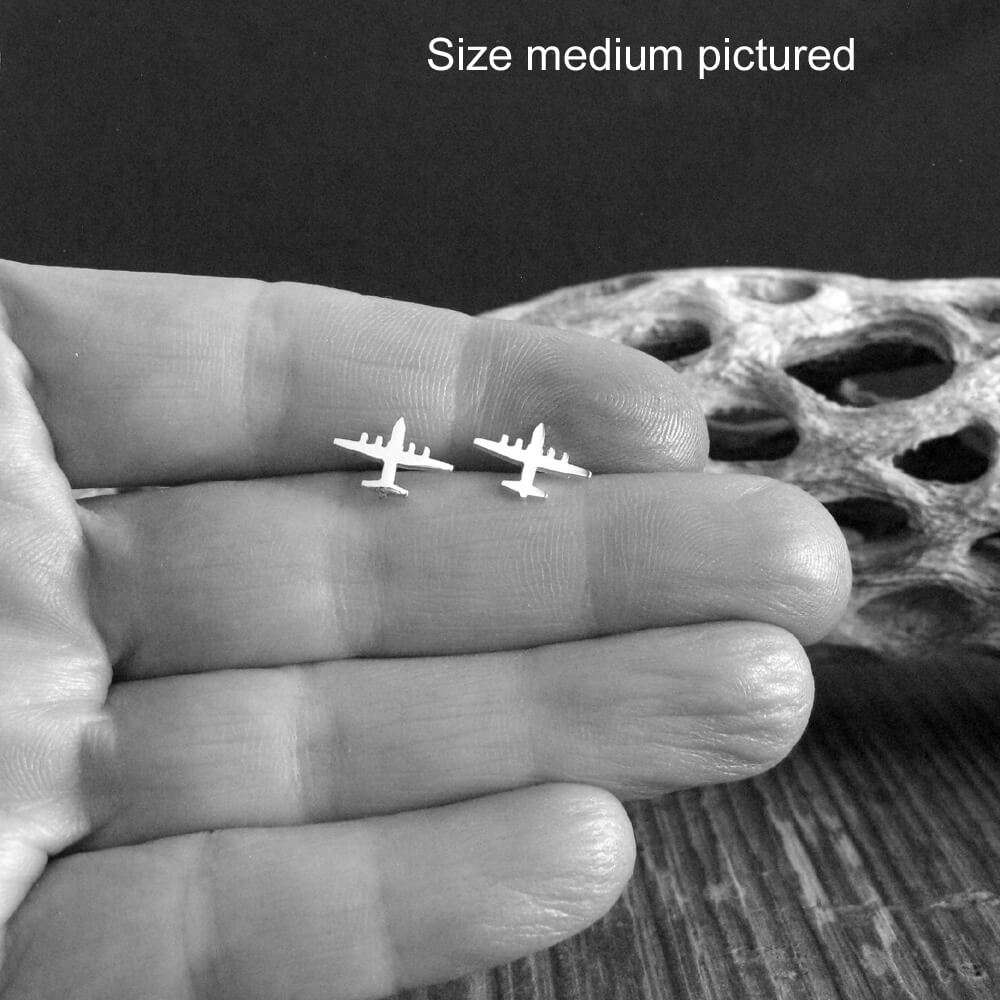 Pair of sterling silver C-130 Hercules Military Airplane stud earrings held in a hand for size reference