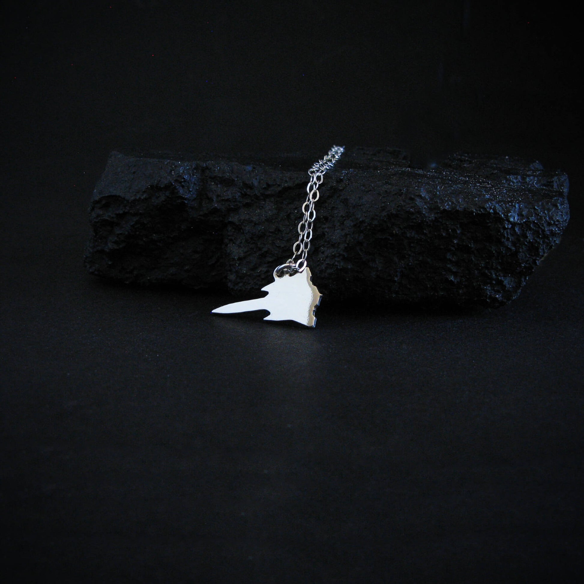 Sterling silver SR-71 Blackbird airplane pendant necklace displayed on black rock aviation jewelry