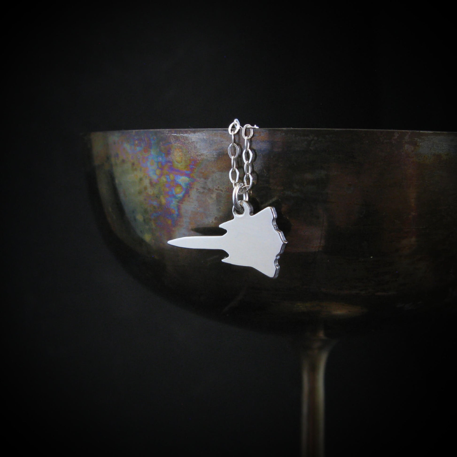 Sterling silver SR-71 Blackbird aircraft pendant necklace draped on wine goblet aviation jewelry