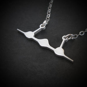 Close-up of sterling silver SR-71 Blackbird front-view jet pendant with fine chain on black background