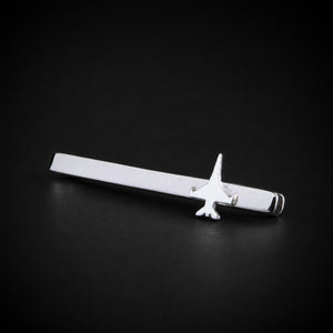 A polished sterling silver tie bar with a F 16 jet fighter, displayed diagonally on a dark black background.