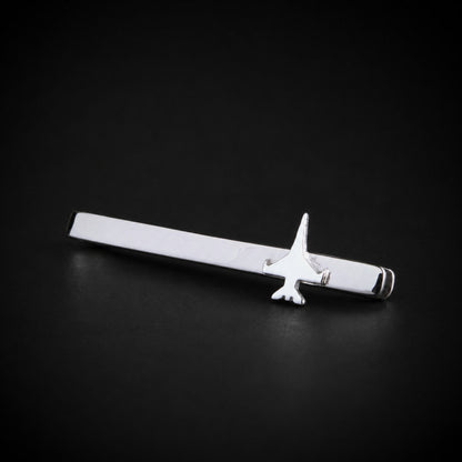 A polished sterling silver tie bar with a F 16 jet fighter, displayed diagonally on a dark black background.