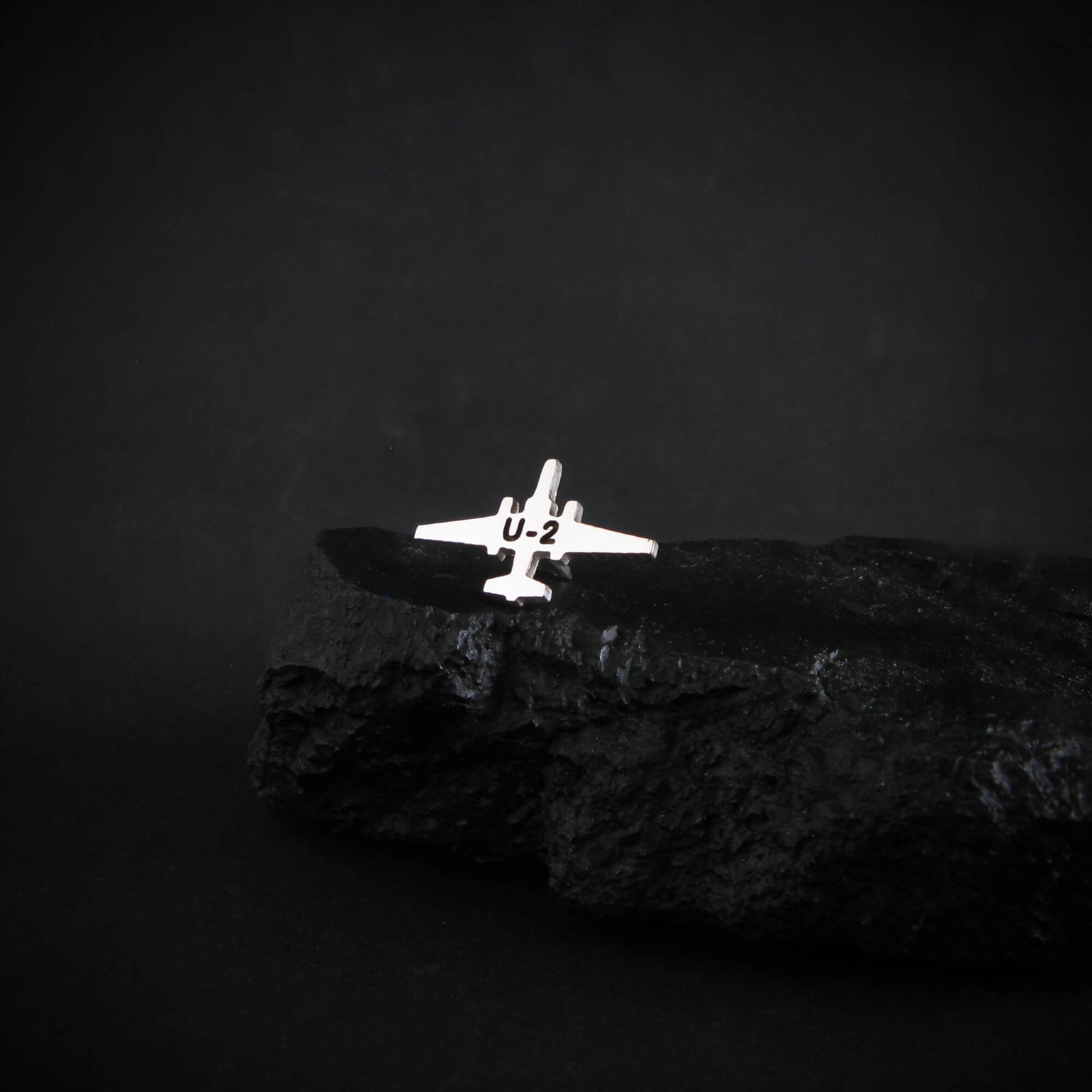Silver U-2 spy plane military tie pin on a dark background