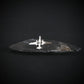 Silver U-2 spy plane tie tack on a dark stone surface with a black background