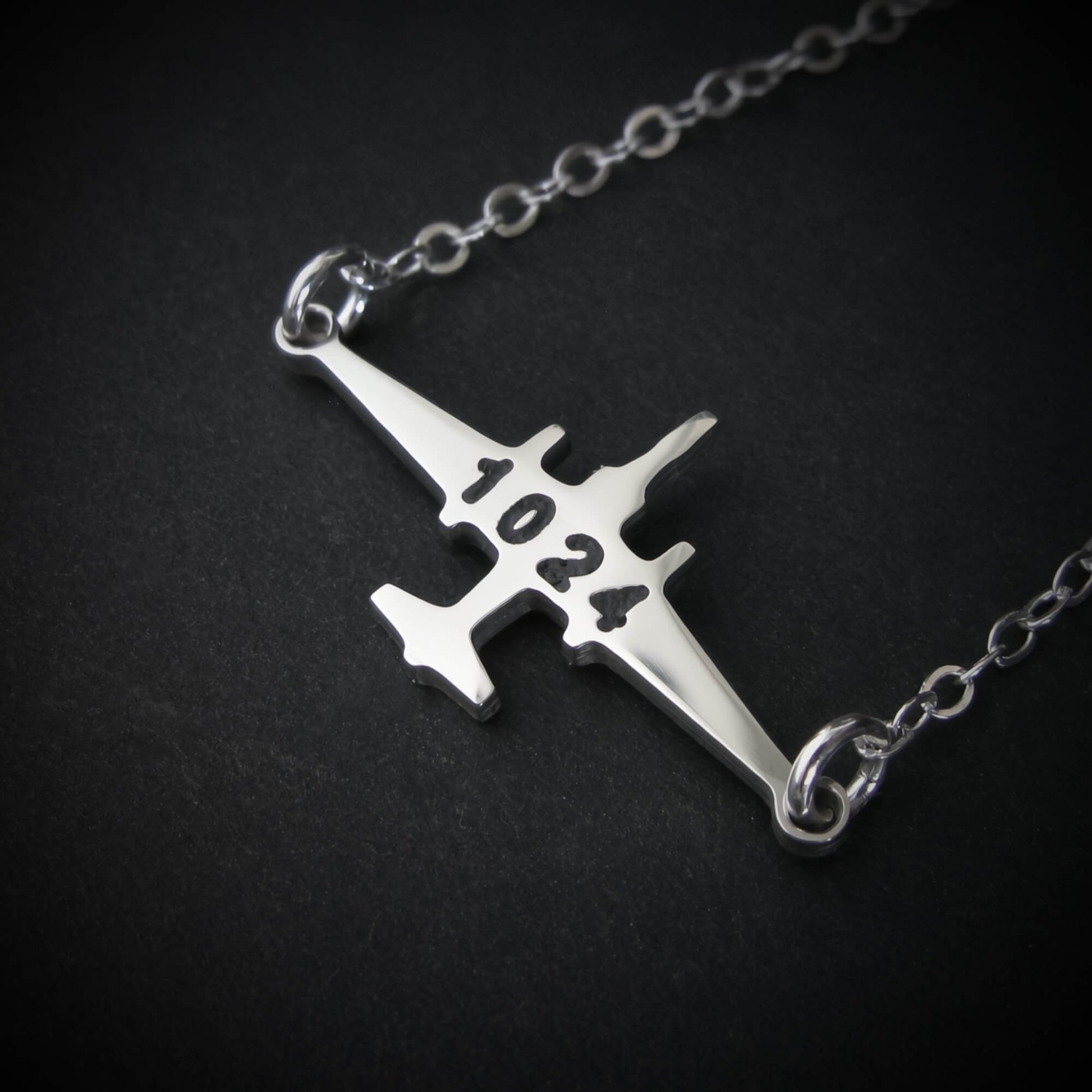 U-2 Dragon Lady military jet pendant necklace in sterling silver with engraved number “1024,” displayed close-up against a dark background.
