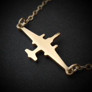 U-2 Dragon Lady military jet pendant necklace in polished 14k gold, displayed close-up against a dark background.