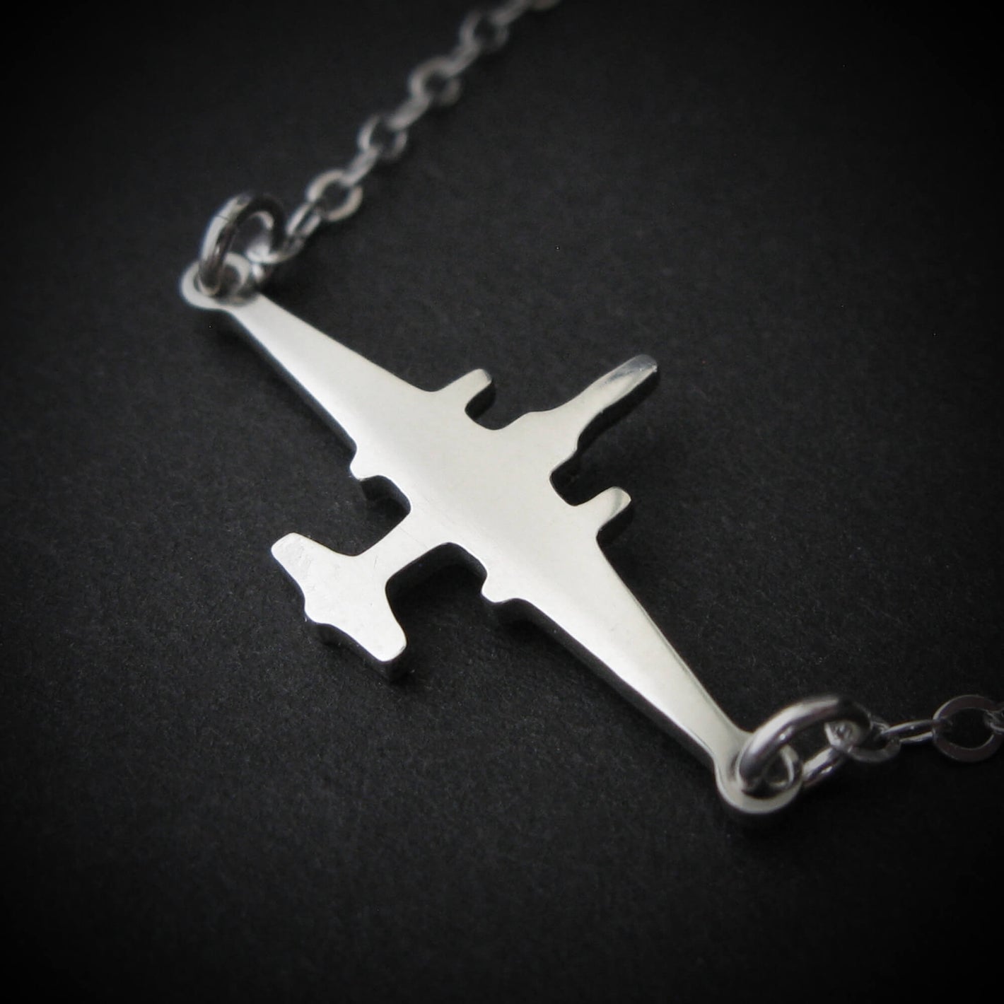 U-2 Dragon Lady military jet pendant necklace in polished sterling silver, displayed close-up against a dark background.