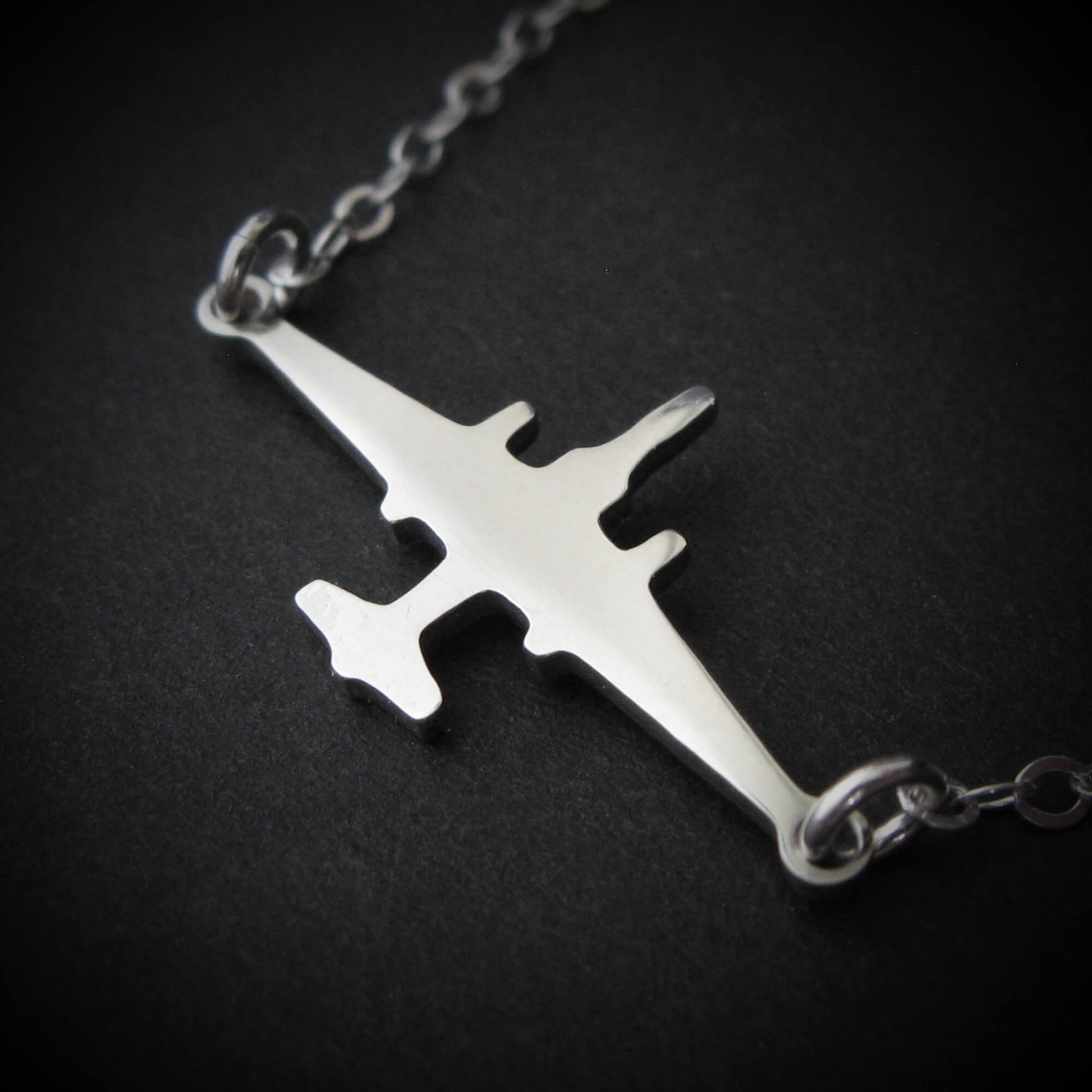 U-2 Dragon Lady military jet pendant necklace in polished sterling silver, displayed close-up against a dark background.