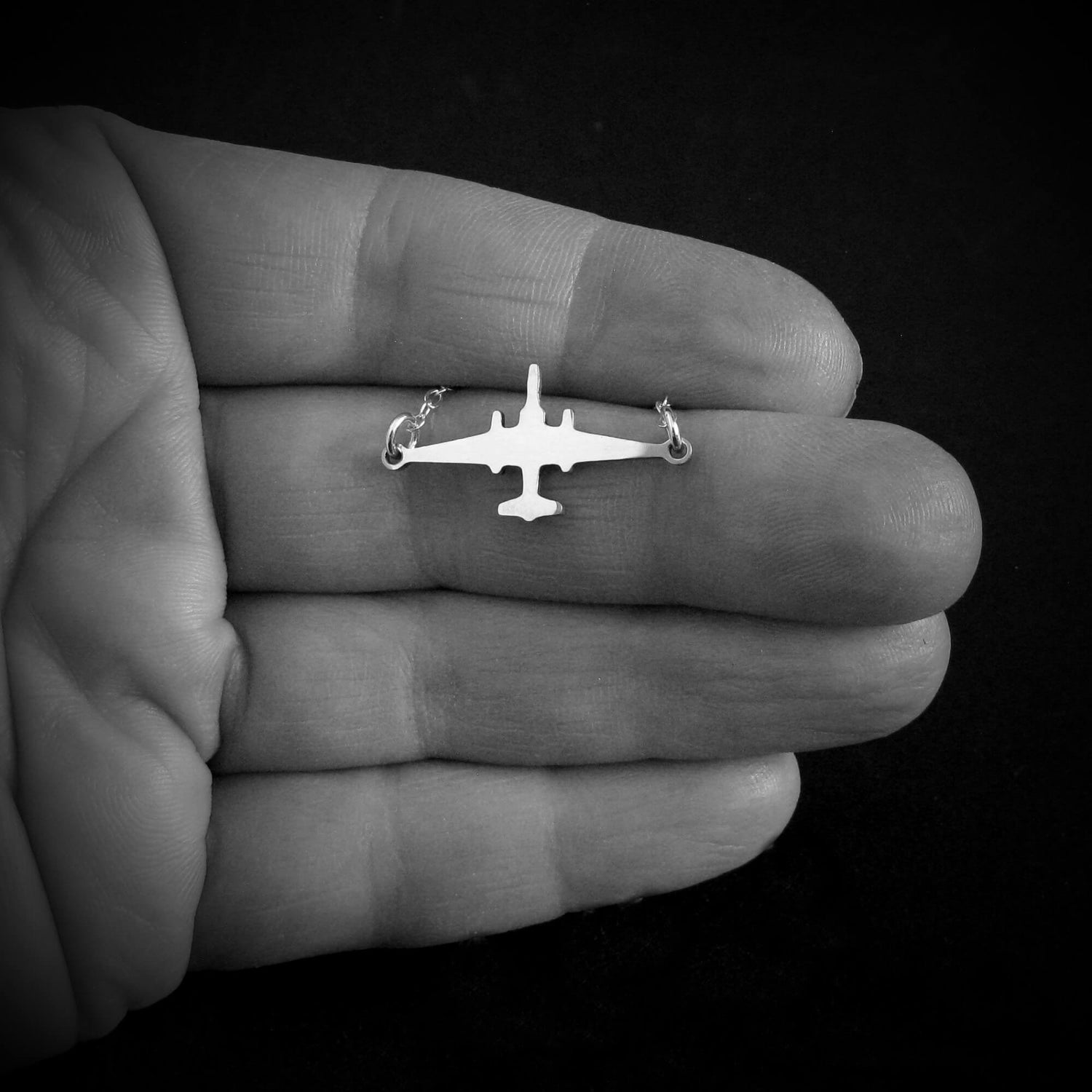 U-2 Dragon Lady military jet pendant necklace in sterling silver, displayed in the palm of a hand against a black background.