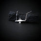 U-2 Dragon Lady military jet pendant necklace in sterling silver, displayed draped over a textured black rock on a dark background.