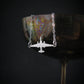 U-2 Dragon Lady military jet pendant necklace in sterling silver, draped over the rim of an iridescent metal wine glass against a dark background.